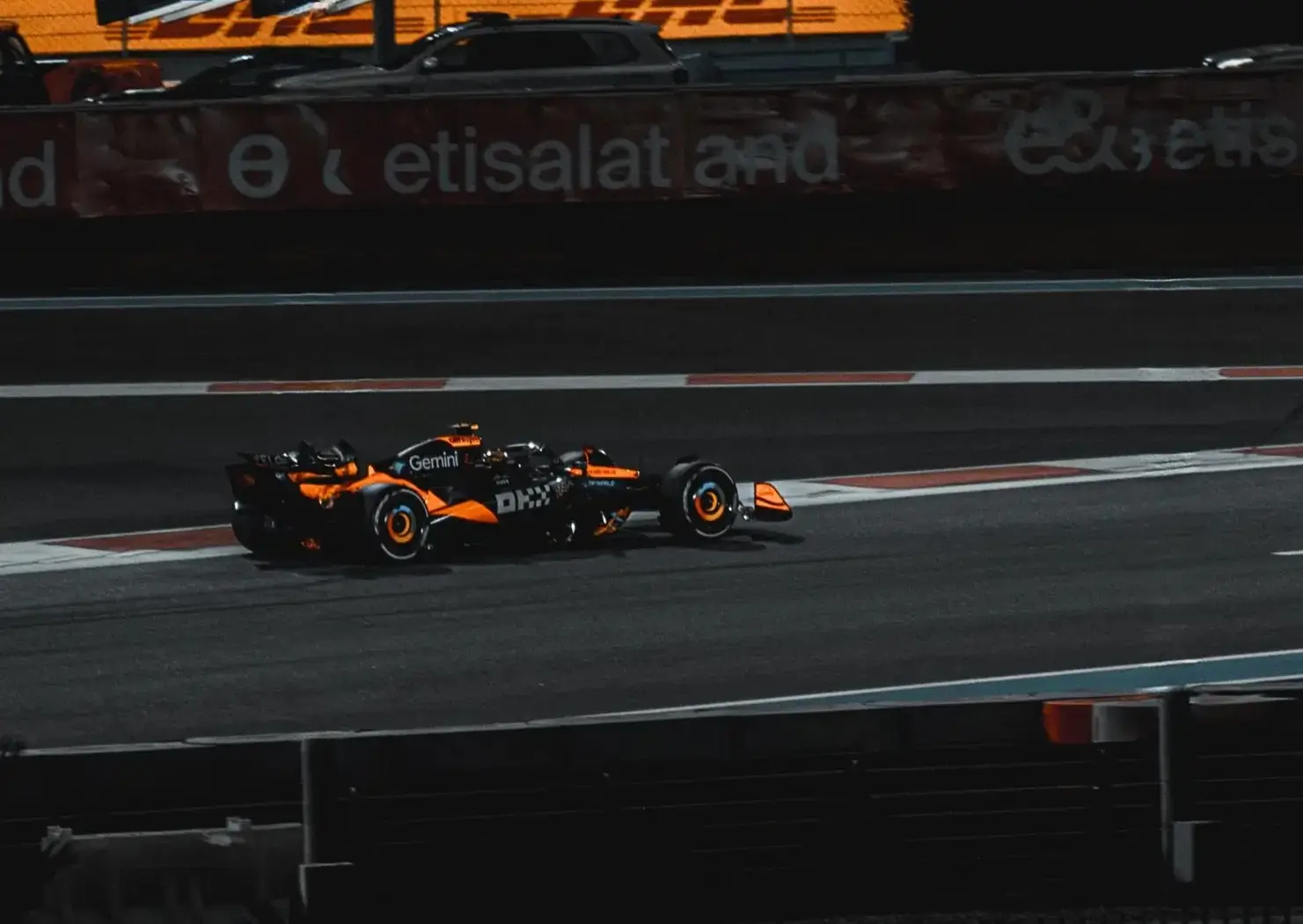 black formula one car with orange stripes on the track mid race